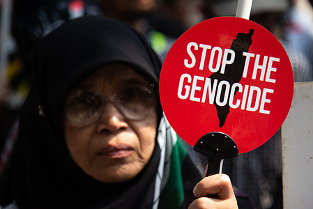 A protester holds a sign saying "Stop The Genocide" during the demonstration outside the Embassy of Israel in Bangkok. Pro-Palestinian protesters gathered in front of the Embassy of Israel in Bangkok to express their support for Palestinians in the Israel-Hamas conflict in Gaza.