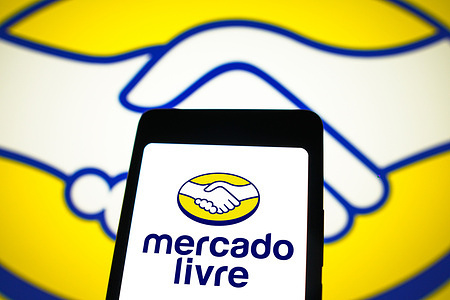 In this photo illustration, the Mercado Livre logo is displayed on a smartphone screen and in the background.