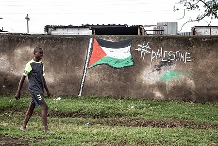 A boy walks past a graffiti featuring a Palestinian flag in Bondeni village near Nakuru Town.