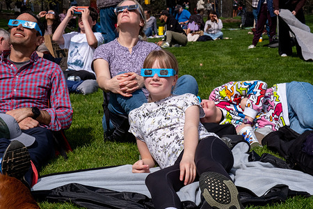 A young girl and her family sit on the grass watching the eclipse with blue glasses. New Yorkers gathered in Central Park to view the solar eclipse. The sun was eclipsed by the moon by 90%, just shy of totality. The last solar eclipse in New York City was in 2017 reaching 70%. The next solar eclipse for the city will be in 2045 at only 50%. New Yorkers will have to wait until May, 2079 for totality.