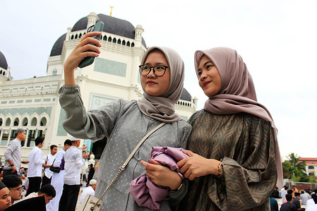 Muslim women take a selfie after performing Eid al-Fitr prayers at the Al Mashun Grand Mosque in Medan.