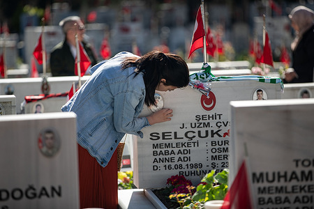 A woman seen cleaning the gravestone. The families of the martyrs came to the Edirnekapi Martyrs' Cemetery on the first day of Eid al-Fitr to visit. Families prayed at the graves of the martyrs and read the Qur'an.