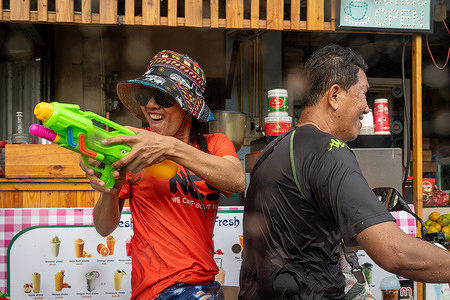 An Asian couple on a motorbike seen having fun with a water gun during the Songkran, Thailand's traditional New Year festival. Songkran, celebrated from April 13th to 15th, is Thailand's lively New Year festival known for its water fights, cultural customs, and festive gatherings. UNESCO has honored Songkran as part of humanity's intangible cultural heritage, highlighting its importance.