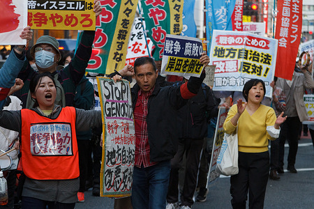 People carry signs calling for Palestinian rights as several hundred people take part in an anti-war protest in the streets of Shinjuku. The protest was organized by left-wing groups and broadly called for an end to the war in Gaza along with anti-government messages concerning the revision of Japan's constitution and the war in Ukraine.