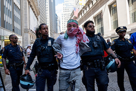 NYPD arrest a protester wearing a kefiyah and a green Hamas band on his head during the rally. Pro-Palestinian activist group Within Our lifetime staged a protest at 11 Wall Street. The protest later attempted to march across the Brooklyn Bridge as part of a multi-city/multi-country attempt to create an “economic blockade” in solidarity with Palestine. Several arrests were made.