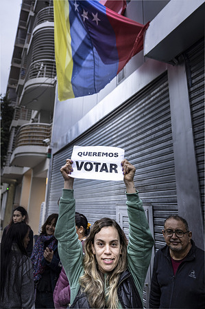 A young Venezuelan woman holds a sign saying "We want to vote" at the door of the closed Embassy during the demonstration. A group of Venezuelan residents in Argentina demonstrated their desire to vote at the door of their Embassy. In spite of the restricted hours for the attention of migrants, the obstacles and the imposition of requirements that exceed what is established by law, the Venezuelan diaspora in Argentina came to demand their right to register in the Electoral Registry to be able to vote against the dictatorship of Nicolás Maduro.