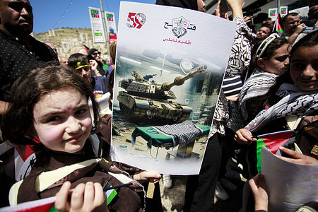 A Palestinian holds a placard during a protest against the massacres committed by Israeli forces in Gaza City.