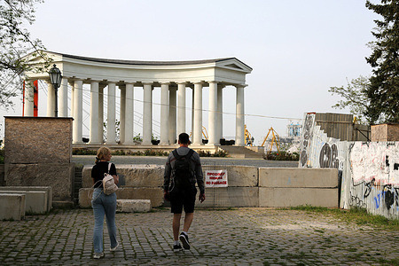 A couple of people approach a concrete barrier and a sign with an inscription limiting the passage to the Vorontsov Colonnade at the end of Prymorskyi Boulevard. The Vorontsov Palace is a 19th-century palace and colonnade in Odesa, Ukraine, at the end of the Prymorskyi Boulevard pedestrian walkway is closed to the public since the beginning of the full-scale invasion of the Russian Federation into the territory of Ukraine.
