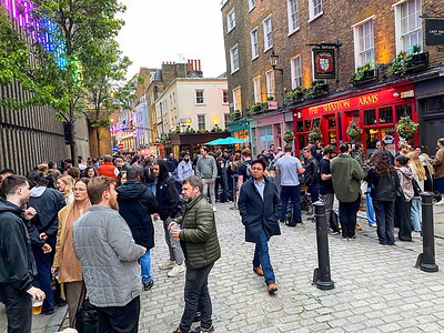 People gather outside pubs on Carnaby Street.