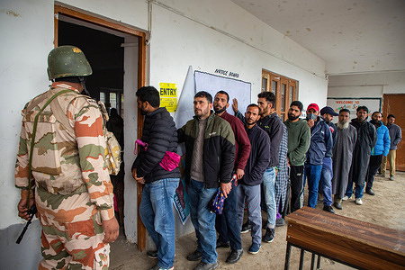 An Indian paramilitary soldier stands on guard as people wait in a queue to cast their votes outside a polling station during the first phase of the Lok Sabha, or lower house, of the Indian parliamentary elections in a hilly village in Banihal, an area in the Ramban district of Udhampur parliamentary constituency. The 2024 Lok Sabha (lower house of Parliament) parliamentary elections mark the first major election in Jammu and Kashmir since New Delhi revoked Article 370, the region's special semi-autonomous status, in 2019. Voting in India, the world's largest democracy, is scheduled to be conducted in seven phases between April 19 and June 1, 2024. With over 970 million voters, comprising more than 10% of the world's population, the electorate will choose 543 members for the lower house of Parliament for a term of five years.