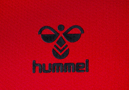 In this photo illustration, Hummel International Sport & Leisure A/S logo seen displayed on a sportswear. 
Hummel is a German-founded Danish manufacturing company of sportswear