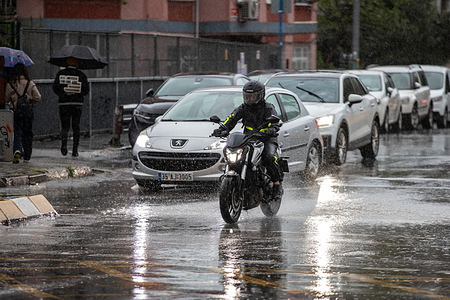 A man on a motor cycle at the traffic lights in Kadikoy under rain. People had difficult times as heavy rain took its toll in Istanbul.