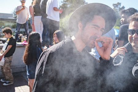 A man smokes at Memorial Glade in UC Berkeley Campus. April 20th is known as Marijuana Day in the United States of America and people celebrate by smoking at 4:20 p.m. every year. At the University of California, Berkeley campus, thousands of people gathered and celebrate Marijuana Day. Most people who celebrate here are the students of the University of California. People here count down and smoke together at 4:20 p.m. on April 20th.