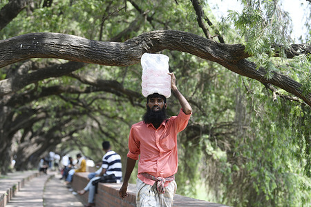 A salesman selling drinking water in a park during a high-temperature day in Dhaka. Bangladesh is experiencing a blistering summer heatwave, marking the peak of the year's hottest season. In Dhaka, people are feeling drained by the unbearable heat.