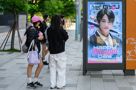 K-pop fans take pictures of a billboard of Hybe's singer Mingyu in front of the Hybe building in Seoul. South Korea's largest K-pop company Hybe has launched an audit of the management at ADOR, the subsidiary label behind NewJeans, a top K-pop girl group, on suspicions that the label sought to break away from Hybe, according to industry sources.
The sources said the audit targets ADOR's CEO, Min Hee-jin, and another executive of the company whose identity has not be disclosed, over their suspected attempt to seize control of the company.