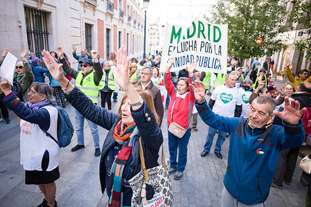 Protesters raise their hands and march with a banner during a demonstration for public health in the center of Madrid. Activists from neighborhood movements in the towns and neighborhoods of Madrid submitted more than 7,000 complaints to the Government of the community of Madrid, demanding that the autonomous Administration not be abandoned and that resources not be diverted to private healthcare.