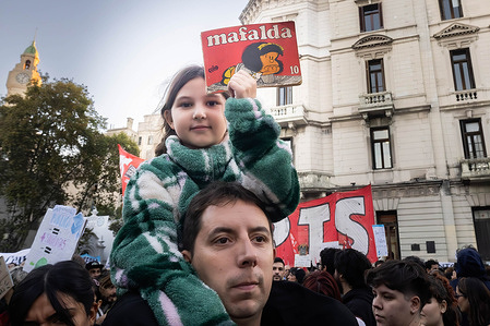 A little girl on her father's shoulders lifts the book of Mafalda, a classic Argentine cartoon during the rally. Protesters in favor of public and free education are protesting against budget cuts. The gathering began at various points in the city before converging in Plaza de Mayo around 5 pm. The protest was repeated in different parts of the country.