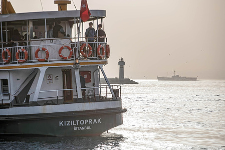 People standing in the open area of the ferry approaching the Kadikoy pier. Desert dust overflow affected a large part of Turkey, including Istanbul where a decrease in visibility and a decrease in air quality was experienced.