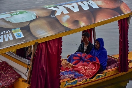 Indian tourists hold blanket as they travel in a boat after a heavy rainfall in Srinagar. Heavy rainfall is expected in most places of Jammu and Kashmir during the next 48hrs. Moderate to heavy snowfall is also expected over the higher reaches of the valley.