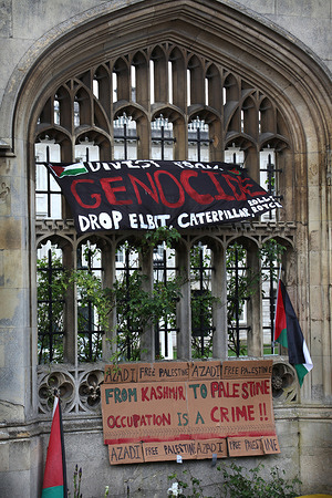 Students and their supporters hang a banner saying ’Divest From Genocide’ in their camp. A protest camp in support of Palestine has been set up outside King’s College, Cambridge. Those occupying the camp are calling on the university to conduct an ethical audit, terminate all investments, endowments research collaborations with any organisation that is complicit in the Israeli occupation of Palestine and genocide in Gaza and become a University of Sanctuary for Palestinian refugees and support Palestinian students and academics. Protesters are determined to stay in occupation until their demands are met