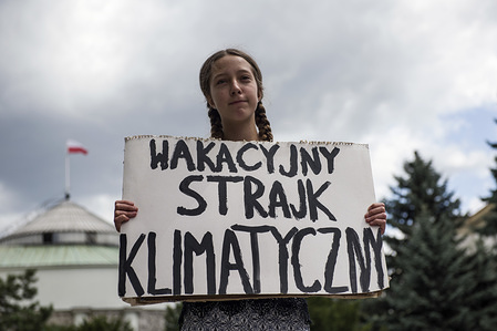 Inga Zasowska, the 13 year old Polish girl seen holding a placard that reads "Holiday Climate Strike" while protesting outside the Polish Parliament.
13-year-old Inga Zasowska started the Holiday Climate Strike last week. She sat in front of the Parliament building to convince politicians to limit global warming. She is planning to protest outside the Parliament every Friday throughout July. 
Inga's action is inspired by Greta Thunberg, a 16 year old climate change activist from Sweden who has expressed her support for the strike of the Polish girl on her Facebook profile.
