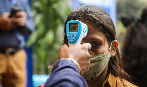A health worker uses a thermal gun to check a volunteer's temperature during a nationwide dry run for Covid-19 vaccine at the health care center at South Delhi Municipal Corporation Darya Ganj.Health workers receive dummy vaccines as part of the dry run to test the mechanisms and reveal possible gaps in the system ahead of the actual vaccination drive. Across India, the dry run was conducted in 116 districts, 259 sites, About 96,000 vaccinators have been trained for this process.
