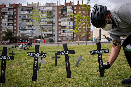 A man puts a cross in commemoration of the deaths in Madrid Rio park.
In the park of Madrid Rio, the Brazilian community held a commemorative act to remember the hundreds of deaths of people from the covid 19 pandemic in Brazil. They also point to Brazilian President Jair Bolsonaro, of genocide and blame him for the tragedy and poor management of the pandemic.
