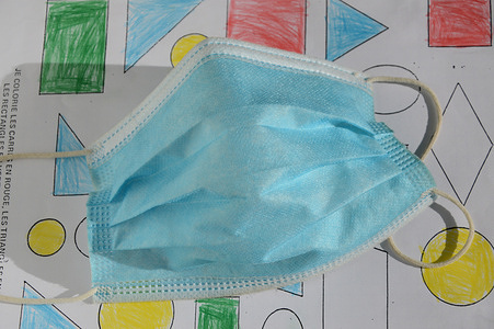 A surgical mask seen lying on a school notebook.
Thanks to a drop below the 50 mark in the number of positive Covid-19 cases per 100,000 inhabitants for 5 consecutive days in 68 French departments, students are exempt from wearing a mask at primary school in France.