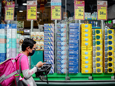 A food delivery man wearing a face mask as a preventive measure against the spread of coronavirus walks past a pharmacy selling various face masks.Malaysia is currently in the recovery phase of Covid-19 which began in the early October by maintaining several Standard Operation Procedures (SOPs) to curb the spread of Covid-19 infection.