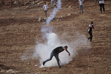 A Palestinian protester throws back a teargas canister at Israeli soldiers during a demonstration against Israeli settlements in the village of Beit Dajan near the West Bank city of Nablus.