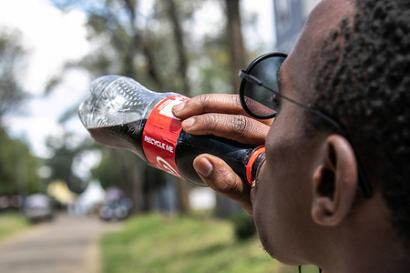 In this photo illustration a man seen drinking Coca-cola.An average of 38% of plastic waste collected near Lake Nakuru National Park, a UNESCO World Heritage Site, are from US based companies with Coca-cola accounting for 44% of bottles collected and audited by Unwaste.io, a UK based social enterprise, other international audits have cited Coca-cola as the biggest plastic waste contributor. Environmental lobby groups are urging companies to take responsibility for the end of life of their products to protect the environment.