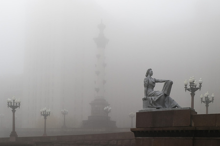A reading woman sculpture in front of the main entrance of Moscow State University during a heavy fog in Moscow.