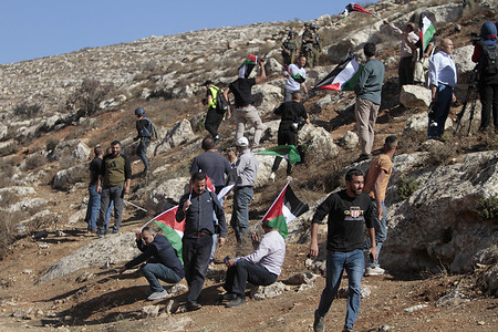 Palestinian protesters hold flags during the demonstration against Israeli settlements in the village of Beit Dajan near the West Bank city of Nablus.