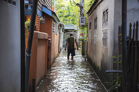 Koh Kret resident walks through a flooded alley.
After Dianmu storm, Lionrock tropical storm and Kompasu storm, 13 provinces were affected by tidal sea level causing floods. Koh Kret a knowable cultural travelling destination, riverside community and River island in Nonthaburi are some of the areas affected.