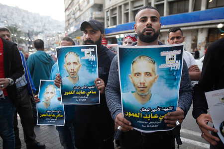 Palestinians hold portraits of Sami Amour, a detainee who died in Israeli detention, as they participate in a solidarity demonstration with prisoners on hunger strike in Israeli prisons in the occupied West Bank city of Nablus.