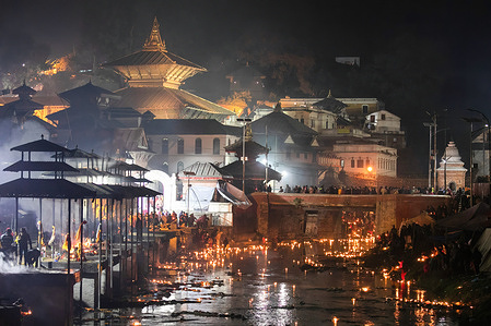 The oil lamps float in the Bagmati River next to the Pasupatinath temple during Bala Chaturdashi festival.
Nepalese Hindu Devotees celebrate the festival by lighting oil lamps and scattering seven types of grains known as "sat biu" along a route at the temple to honor the departed.