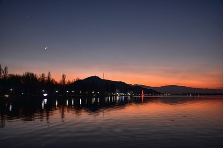 The moon rises over the Dal Lake during a cold evening.
After a day of rain and snow, weather started improving in Kashmir valley. The forecast is mainly dry weather for the next ten days.