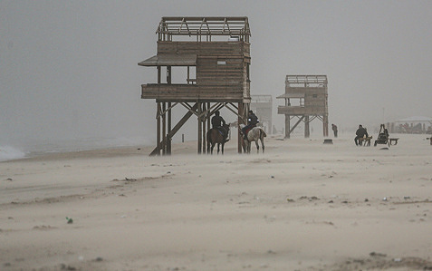 Palestinians ride horses along the beach in Gaza during the stormy weather.
