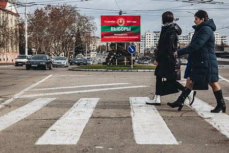 People walk across the road past a billboard advertising the presidential election campaigns in Tiraspol.
Tiraspol is the capital of Transnistria (de facto), a breakaway state in Moldova which considered an 'unrecognised' State. The city is situated on the eastern bank of the Dniester River and is a regional focal point for light industry, such as the manufacture of furniture and electrical goods. The Presidential election is due to be held on December 12th 2021.