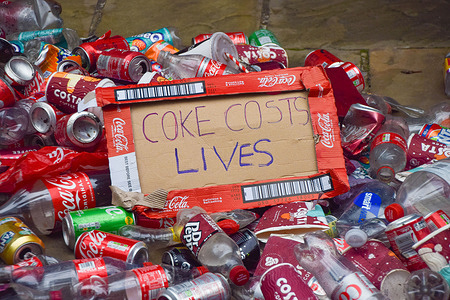 'Coke Costs Lives' placard made out of a Coke box is seen among plastic bottles and tin cans during the demonstration.
Extinction Rebellion activists dumped plastic bottles and tin cans outside Coca-Cola European Partners headquarters in Uxbridge. In addition to global pollution, the activists accuse the soft drinks giant of manipulation, human rights violations and corporate greed.
