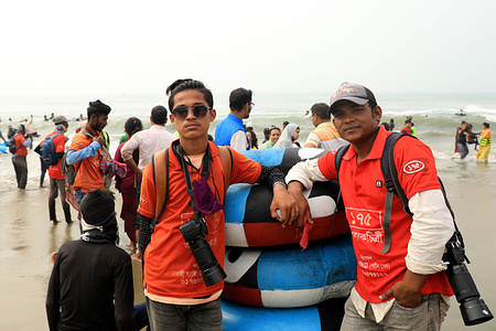 Two photographers pose for a photo at the Cox's Bazar beach.
The Cox’s Bazar sea beach is the home of the country’s largest photographers’ community. More than a thousand photographers make a living working at the beach. They take photos of the tourists and sell them. Each day, they can earn from BDT 500 to BDT 600 ($6-7USD). Nearly half of these photographers are full-time manual laborers and photographers by chance.