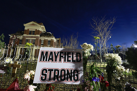 A sign reading, “Mayfield Strong, left where flowers and photos of those who died at a makeshift memorial on a fence surrounding the Graves County courthouse, in Mayfield. 
Multiple nighttime tornadoes struck several Midwest states on December 10, causing widespread destruction and multiple casualties.