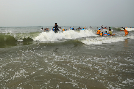 People in the water enjoying a gentle sea breeze on a perfect sunny day without clouds.
Cox's Bazar sea beach is 152 km from Chittagong city to the south and is 414 km from Dhaka. It is the largest tourist destination in Bangladesh. Plans are afoot to set up a railway line from Chittagong to Cox's Bazar.