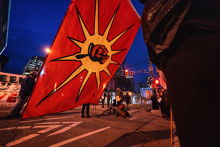 An activist holds up a Mohawk Warrior flag during the demonstration.Protesters gather outside of the RBC Centre in downtown in solidarity with Wetísuwetíen Land Defenders. Their demands are for RBC to defund the Coastal GasLink pipeline and respect Indigenous sovereignty.