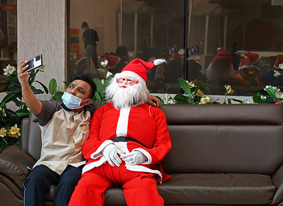 A man takes a selfie with Santa Claus, during a hand hygiene education event at Wockhardt hospital.
