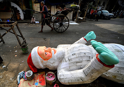 A handpull rickshaw seen passing in front of a giant effigy of Santa Claus.