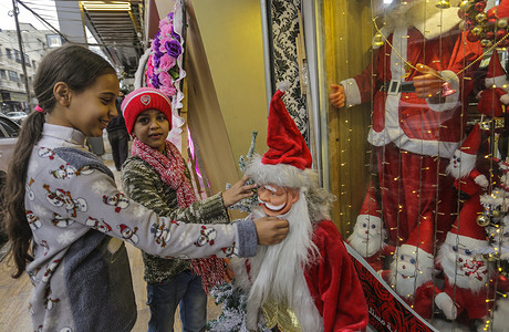Palestinian children are seen checking the price of Santa Claus at a store before the upcoming Christmas holiday in Gaza City.