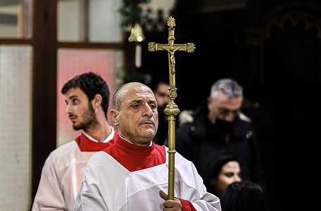 An altar server carries a crucifix during the midnight mass on Christmas eve at the Latin Monastery Catholic Church.