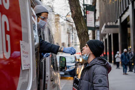 A health worker collects a swab sample from a person for COVID-19 testing at a mobile COVID-19 testing site in midtown Manhattan. 
Mobile testing clinics offer free PCR and rapid antigen testing to residents and visitors.