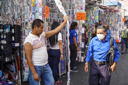 A man walks past a seller of cellphone accessories as people shop for New Year's eve in downtown.